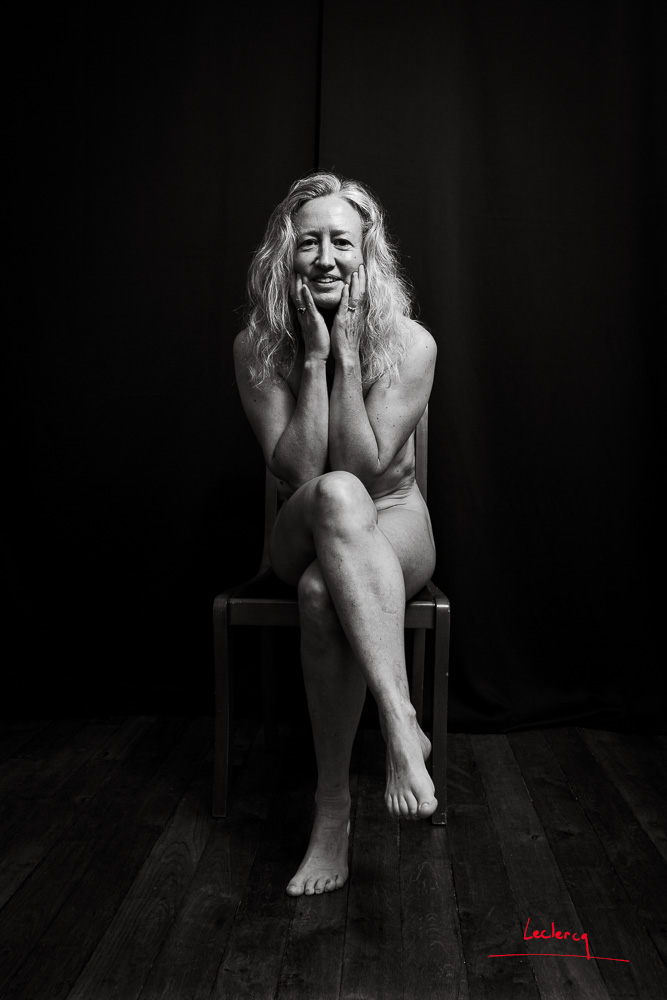 Une femme pose nue assise en studio. Photographie en noir et blanc.