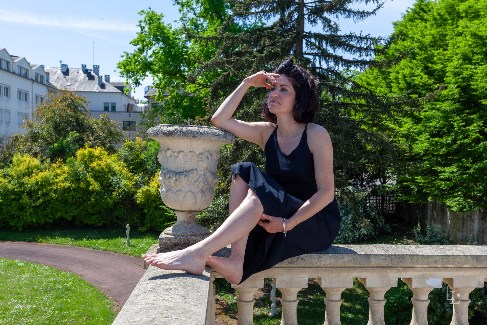 Séance Habillée puis Nue à Chantilly | Nude Élégance 1 Une jeune femme pose sur une balustrade en robe noire.